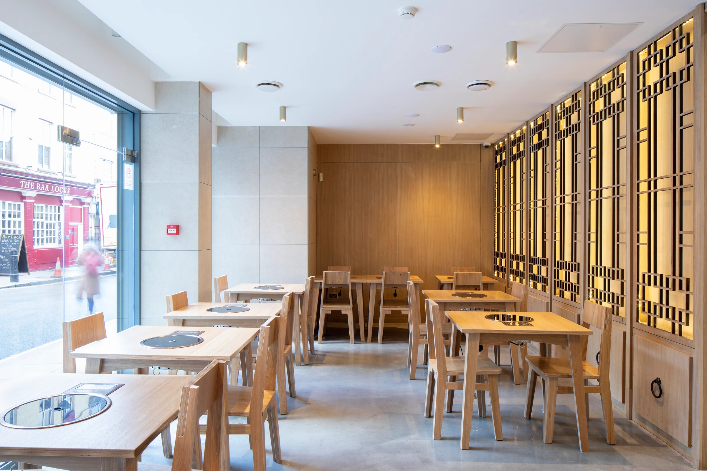 Bari Bari dining room with pale timber furniture and full-height patterned screens.