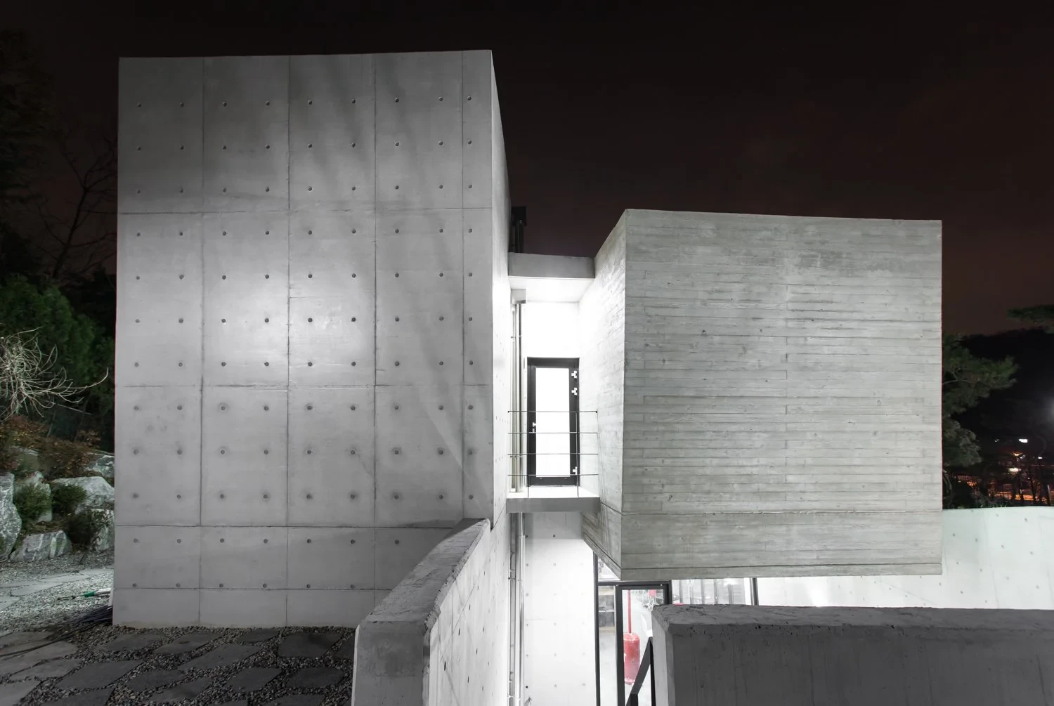 Night view of the Gatehouse concrete volumes and glazed connection.