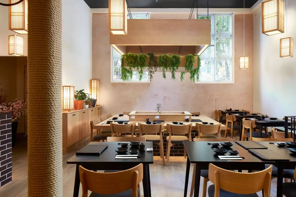Sushinoen dining room with timber chairs, dark tables, hanging lanterns and planting.